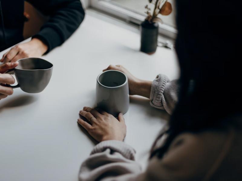 Two people sharing warm mugs at a table