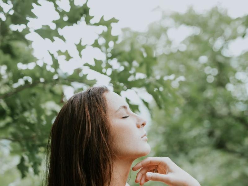 A woman resting with her eyes closed among trees